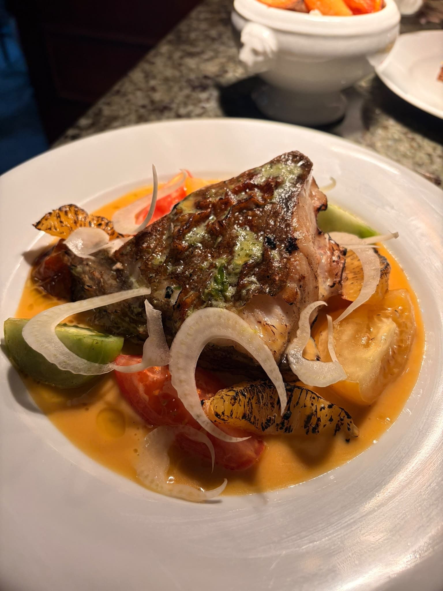 Crisp-skinned fish with herb butter, tomatoes, charred orange and shaved fennel in a light sauce