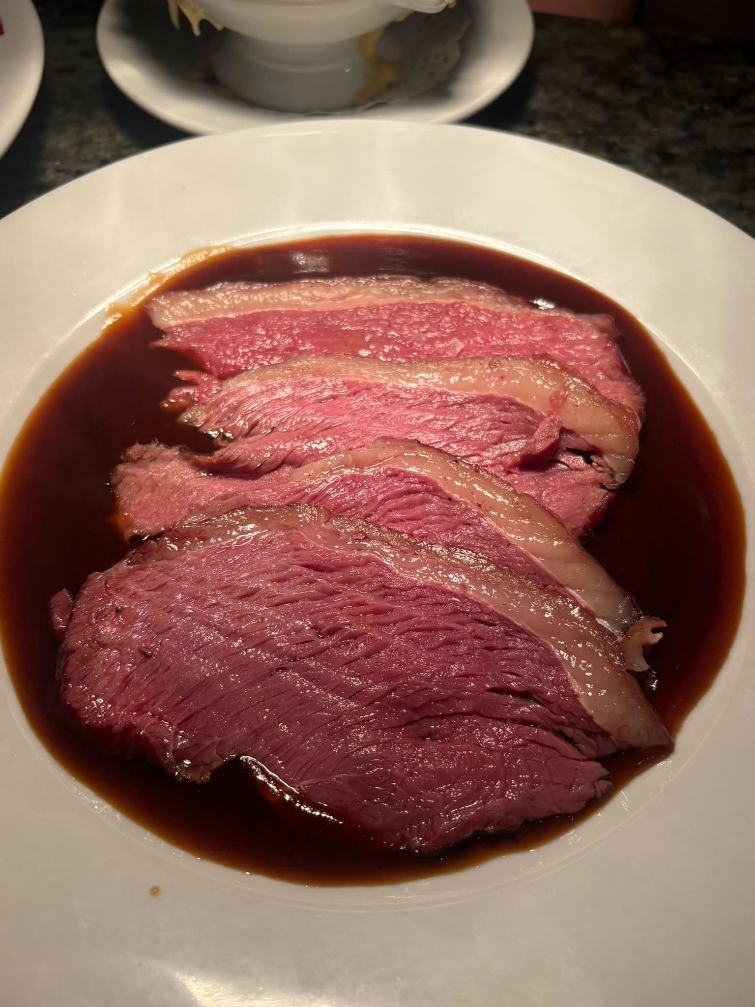 Slices of pink roast beef in a pool of dark gravy